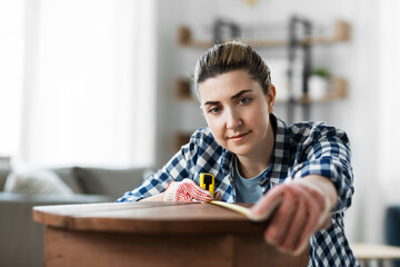 Wall Mural - repair, diy and home improvement concept - woman with ruler measuring old wooden table for renovation