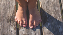 Kid Walking Barefoot On Wood Plank At A Lake. Close Up Feet. Detail Of Kids Legs Walking On Wooden Pathway Barefoot. Playful Child On A River
