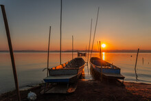 Two Small Boats Moored On The Shore Of The Lake. At Sunset