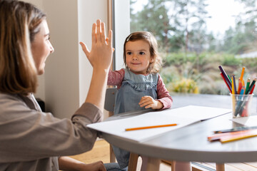 Canvas Print - family, motherhood and leisure concept - mother spending time with her little daughter and making high five gesture at home