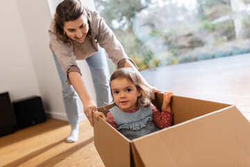 Sticker - family, hygge and people concept - happy mother and little daughter sitting in box playing at home