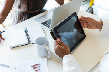 Woman using tablet PC with friend working at home