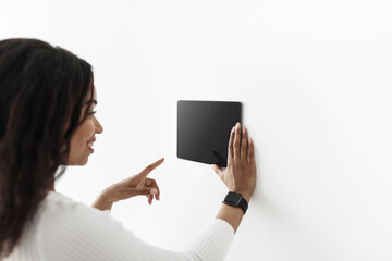 Poster - African american woman using digital tablet with blank black screen with smart home control system app, mockup