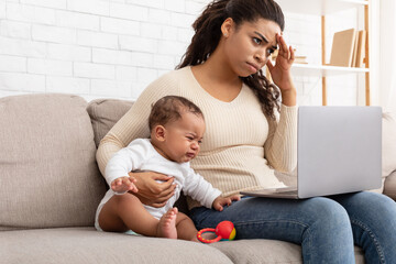 Wall Mural - African Mother Trying Work On Computer While Infant Screaming Indoor