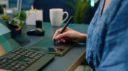 Poster - close up of hand holding stylus on graphic tablet for pictures retouch at desk. photographer using e