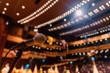 Close Up Of Microphone On The Theater Stage In Concert Hall And Blurred Lights Background