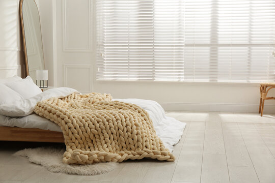Soft chunky knit blanket on bed in light room