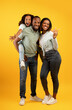 © Prostock-studio - Joyful african american family with cute daughter posing over yellow background, having fun, girl piggybacking dad