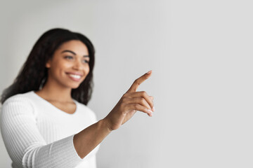 Poster - Smart home interface concept. African american woman pointing finger up in the air pushing button on invisible screen