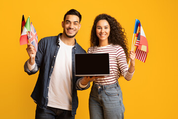Poster - Smiling Arab Couple Holding International Flags And Laptop Computer With Blank Screen