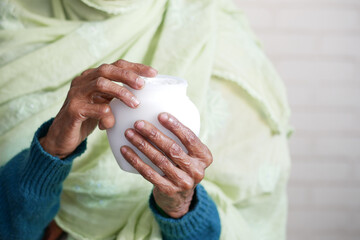 senior woman applying beauty cream onto skin 