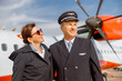 © Kostiantyn - Cheerful aircraft pilot and stewardess standing outdoors at airport