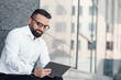 © Prostock-studio - Confident successful mature businessman with digital tablet sitting near office center during break, copy space