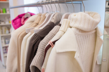 Wall Mural - Pastel knit warm sweaters on white hangers.