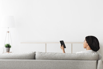 Poster - Happy african american lady controlling home heating temperature with cellphone, copy space on white wall