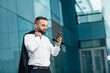 © Prostock-studio - Mature stylish businessman with smartphone in hand reading good message, standing near city office on street, free space