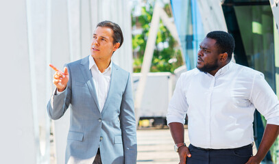 Wall Mural - Finance, business and cooperation concept. Two successful businessmen are talking on the street. Office workers are discussing business issues outdoor.