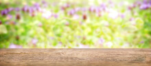 Brown Wooden Table Surface With A Focal Line. In The Background There Is A Defocus Green Grass With Purple Flowers. Copy Space.