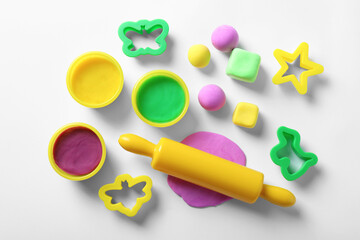 Set of tools and color play dough on white background, top view