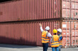 © NVB Stocker - Hispanic man harbor worker talking on the walkie-talkie radio and control loading containers at container warehouse. container yard port of import and export goods