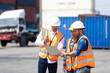 © NVB Stocker - Hispanic man harbor worker talking on the walkie-talkie radio and control loading containers at container warehouse. container yard port of import and export goods