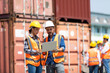 Hispanic Man worker and woman Supervisor checking and control loading Containers box by laptop computer at container yard port of import and export goods. Unity and teamwork concept