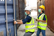 © NVB Stocker - professional team man and woman worker wearing protection face mask during coronavirus and flu outbreak and wearing safety hardhat helmet at container yard or cargo warehouse