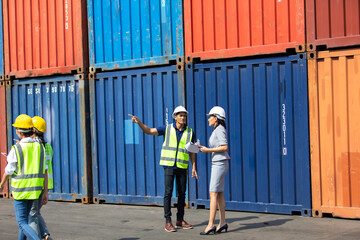 Group of professional dock worker and engineering people wearing hardhat safety helmet and vest working at container yard port of import export. Business teamwork concept