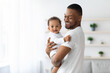 © Prostock-studio - Happiness Of Fatherhood. Young black dad with little baby on hands