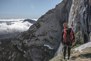 Wall Mural - chica en la montaña con una mochila y mar de nubes de fondo