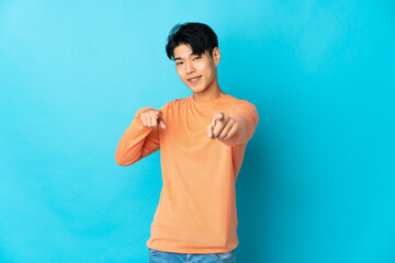 Wall Mural - Young Chinese man isolated on blue background pointing front with happy expression