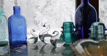 Antique Glass, Jars And Bottles In Front Of A Window With Snow On Trees Outside