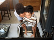 Son is helping mother in the Kitchen, Washing Dishes. African American family.