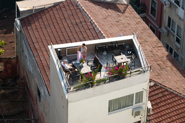 Outdoor terrace in one of the Istanbul apartment. Two men are hanging out on the roof of their house. There is a watermelon on the table.