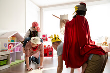 Fathers Piggybacking Daughters In Costumes Playing Sword Fight