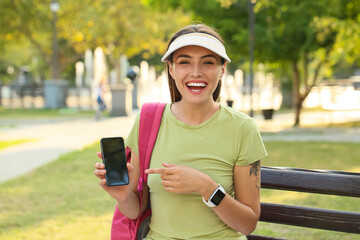 Wall Mural - Young female tourist with mobile phone in park