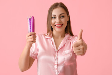 Wall Mural - Young woman with sex toys showing thumb-up on color background