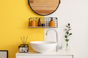 Chest of drawers with sink, shelf and bath supplies near color wall