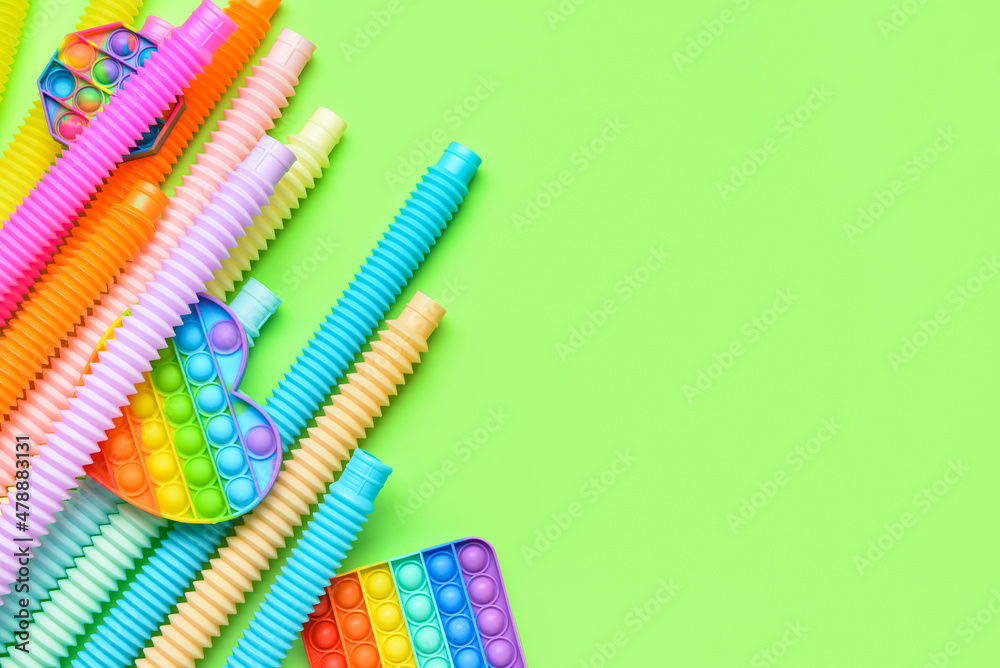 Colorful Pop Tubes and Pop it fidget toys on green background