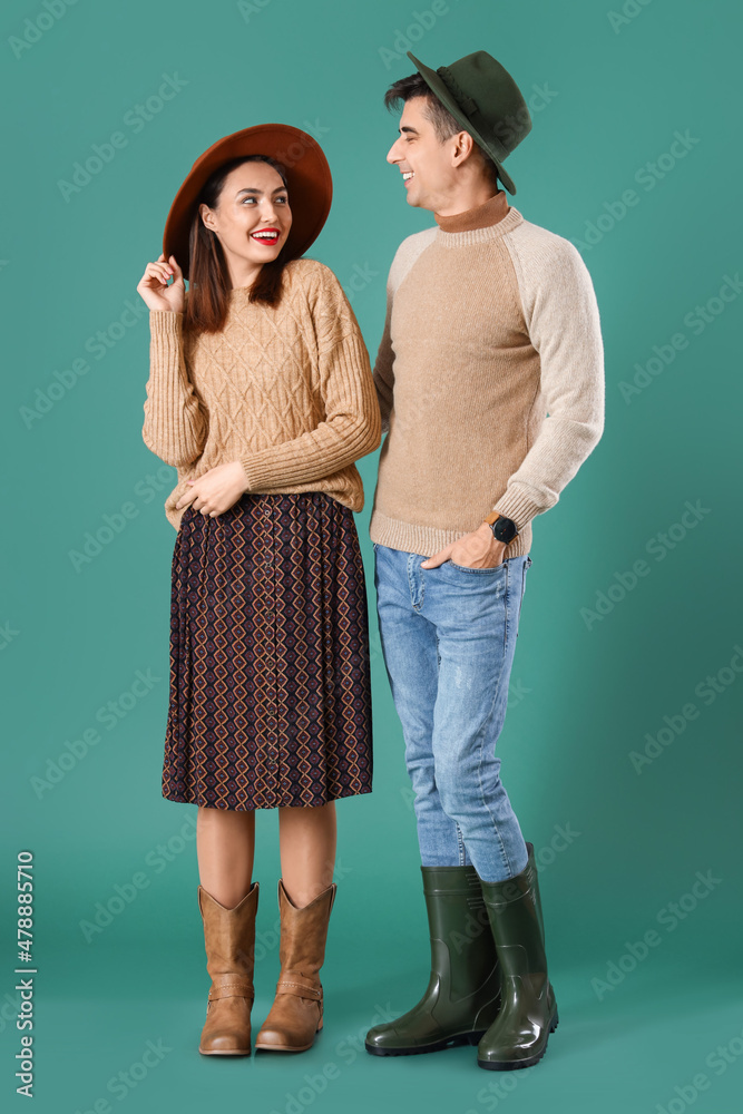 Happy young couple in warm sweaters on color background