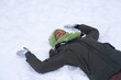 Black African Afro American girl, young unconscious frozen woman is freezing, lying on white snow, having fun. Person is fall, fallen lady to the cold ground because of winter frosty slippery road