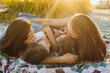 © Kelsey Smith/Stocksy - Lesbian wives on beach blanket with children