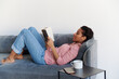 © Elena Kharichkina/Stocksy - Portrait of a relaxed girl reading a book at sofa