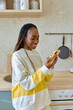 © Tatiana Timofeeva/Stocksy - a woman chatting in a smartphone at home kitchen