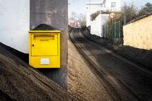 A Yellow Mailbox Surrounded By Volcanic Ash.