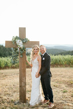 Bride And Groom Standing At Christian Cross