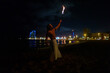 © Igor Kardasov/Stocksy - man doing a fire show on the beach