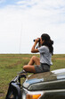 © Kike Arnaiz/Stocksy - Woman looking through binoculars in safari