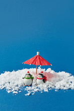 Penguins Figurines In Snow Under Umbrella