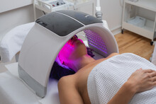 Woman Lying Under A LED Light Facial Therapy Lamp